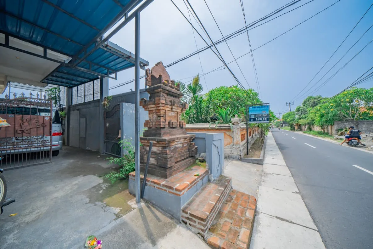 Street entrance of the SAS guest house in Dalung with a parked van and a two-lane road, July 2026