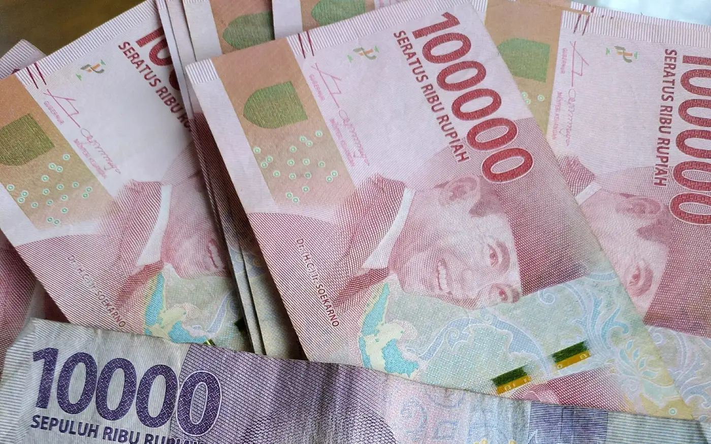 Indonesian rupiah notes: red 100,000s and a purple 10,000